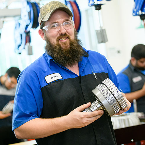 automotive tech student, john, holding car part for camera