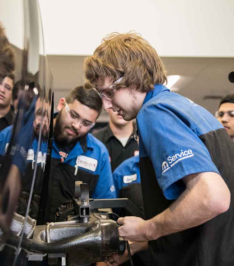 mopar student mechanic putting a part on a car
